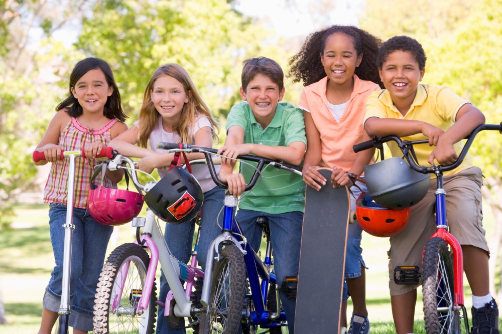 Five young friends with bicycles scooters and skateboard outdoor